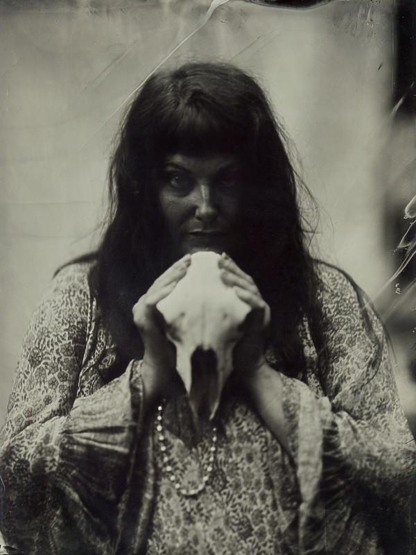 Black and white photograph of a woman holding a sheep skull taken with an antique camera.  